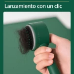 Cepillo de color verde esmeralda con sistema de expulsión de cabello acumulado, sujetado por una mano sobre fondo minimalista del mismo color.