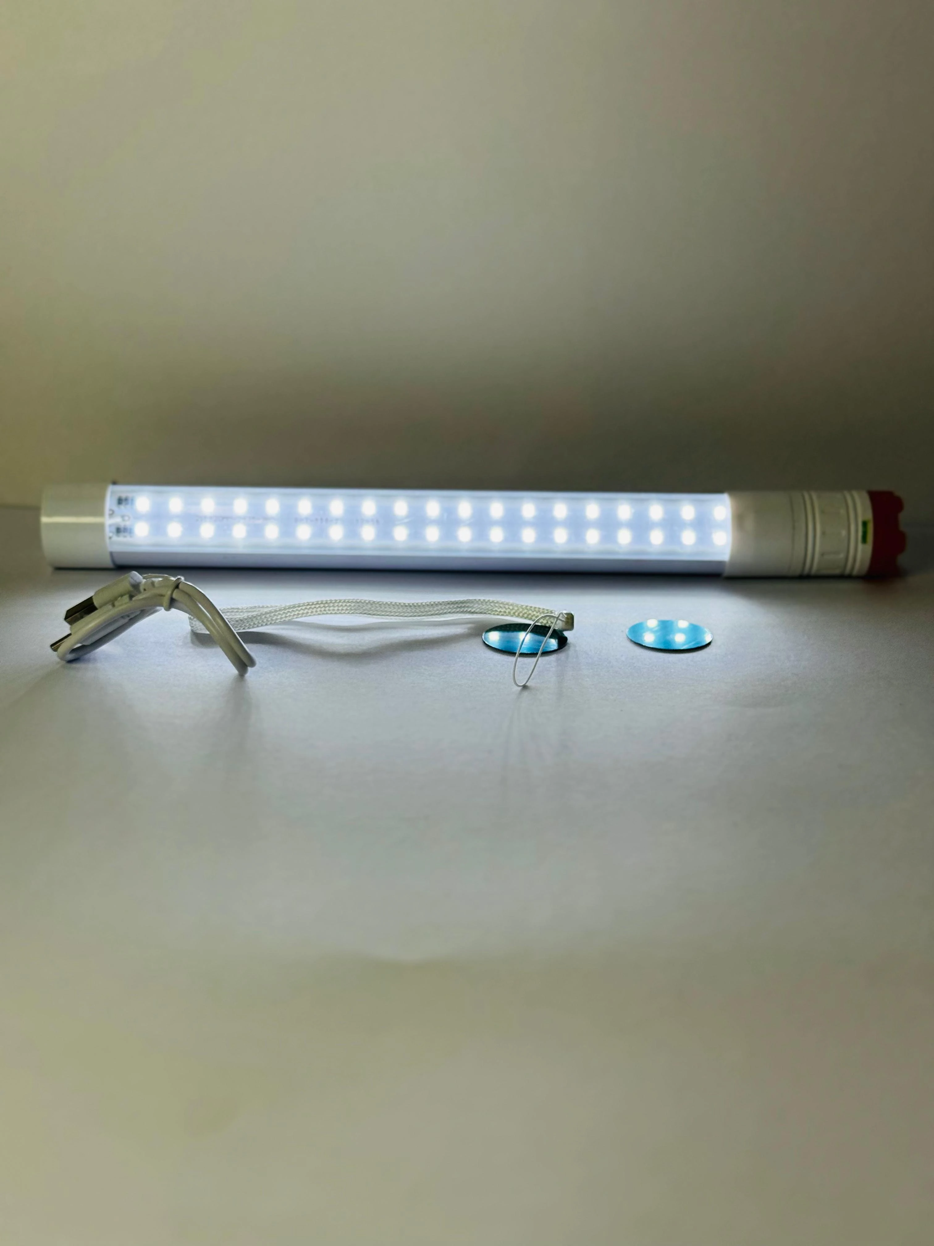 Linterna LED blanca de 27cm con tapa roja, cable USB y dos imanes.