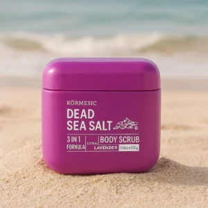 Exfoliante corporal Kormesic Sal de Mar Muerto, 3 en 1, lavanda, en envase morado sobre arena de playa.