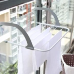 Colgador compacto gris para secar ropa en ventana o balcón, con barras blancas y toallas blancas colgando.