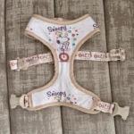 Arnés para perros con estampado de Snoopy, diseño de dos piezas conectadas, correas ajustables con hebillas plásticas color arena y superficie blanca.