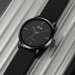 Reloj Scottie 2050 sumergible de silicona negra, diseño minimalista, fondo negro y manecillas plateadas.