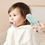 Cortadora de cabello para bebé VGR V-155 color verde menta, diseño silencioso con succión, utilizada por un adulto cerca de la cabeza de un niño pequeño.