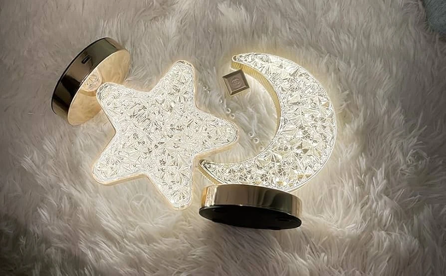 Lámparas de mesa Zo con forma de estrella y luna creciente, diseño con textura de cristal facetado, bases doradas brillantes sobre superficie peluda.