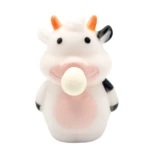 Vaca de silicona blanca con manchas negras y rosadas, cuernos naranjas y bola blanca en la boca.