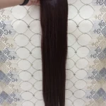 Extensiones de cabello liso color castaño oscuro de 60 cm, sujetas por una banda superior con clips, mostradas sobre un fondo decorativo claro.