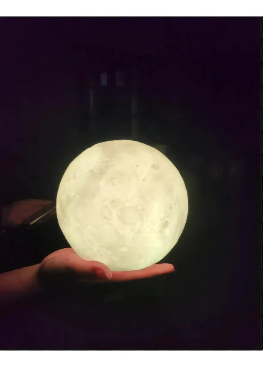 Lámpara LED con forma de luna llena de 15 cm, textura realista de cráteres con luz cálida sostenida sobre una mano en un entorno oscuro.