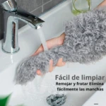 Plumero de microfibra gris suave bajo chorro de agua, ideal para limpiar manchas en el lavabo fácilmente.