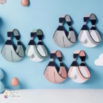 Seis fulares portabebé colgando en la pared en colores pastel y gris.