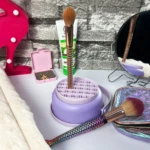 Organizador morado de brochas de maquillaje con asa, escarcha y cepillo de cola de sirena.