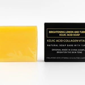 Pastilla de jabón amarillo brillante con ácido kójico y cúrcuma, empaque negro con detalles dorados.