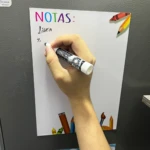 Pizarra magnética con diseño de útiles escolares, mano escribiendo "Lista".