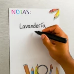 Set de pizarras magnéticas con título "NOTAS" y mano escribiendo "Lavandería", rodeado de útiles escolares.