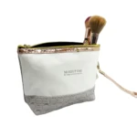 Bolso organizador de maquillaje blanco con base texturizada gris y pinceles visibles.