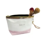 Bolso de maquillaje blanco con base rosa texturizada y dos brochas, ideal para organización.