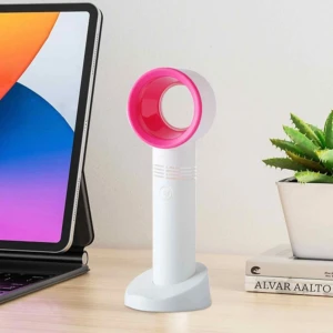 Ventilador de mano sin aspas blanco con borde rosa, sobre base, junto a tablet y libros.