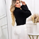 Suéter negro cuello alto para dama, talla única, con jeans blancos.