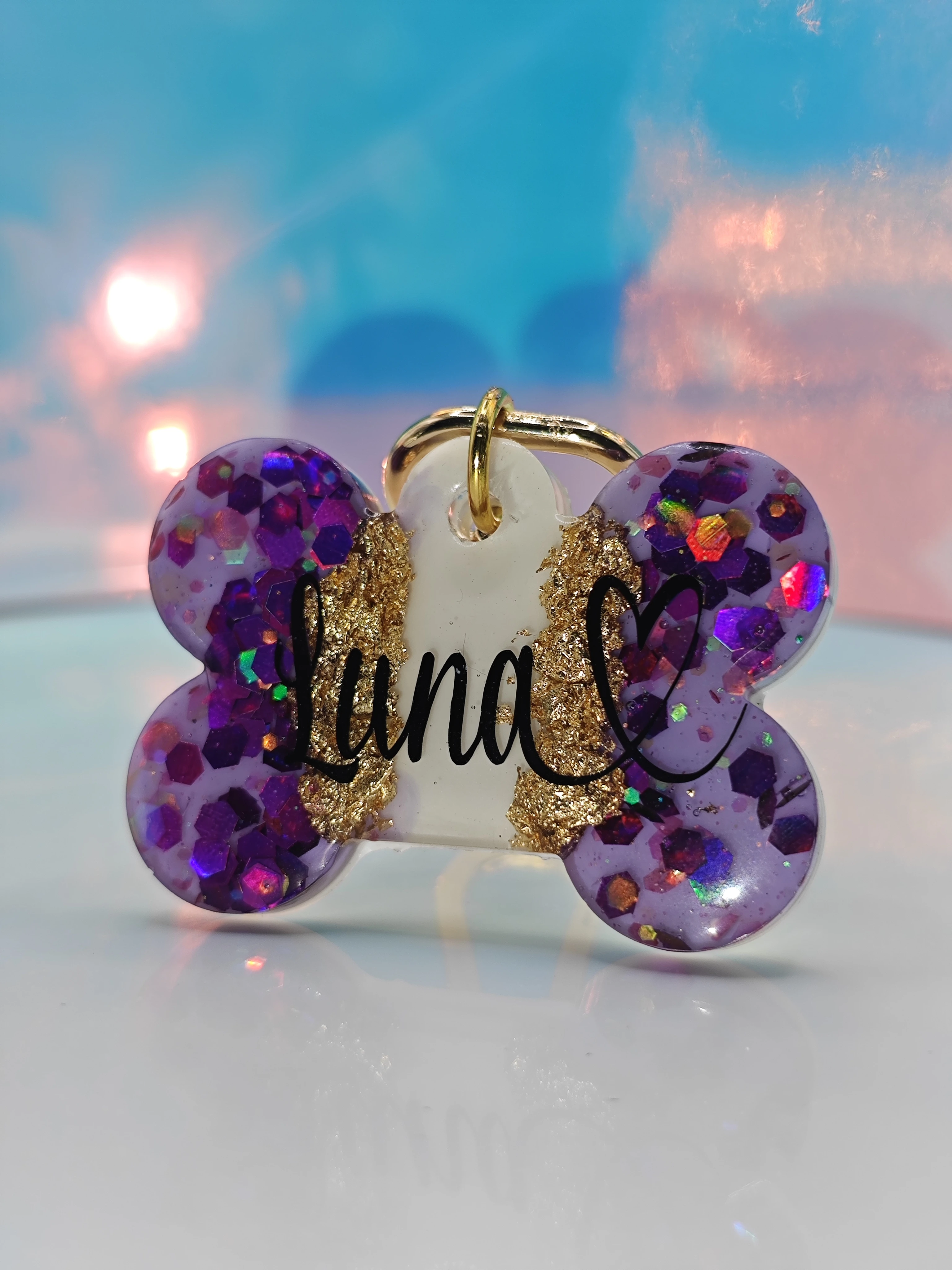 Placa de mascota en forma de hueso morada con glitter y nombre "Luna" en dorado.