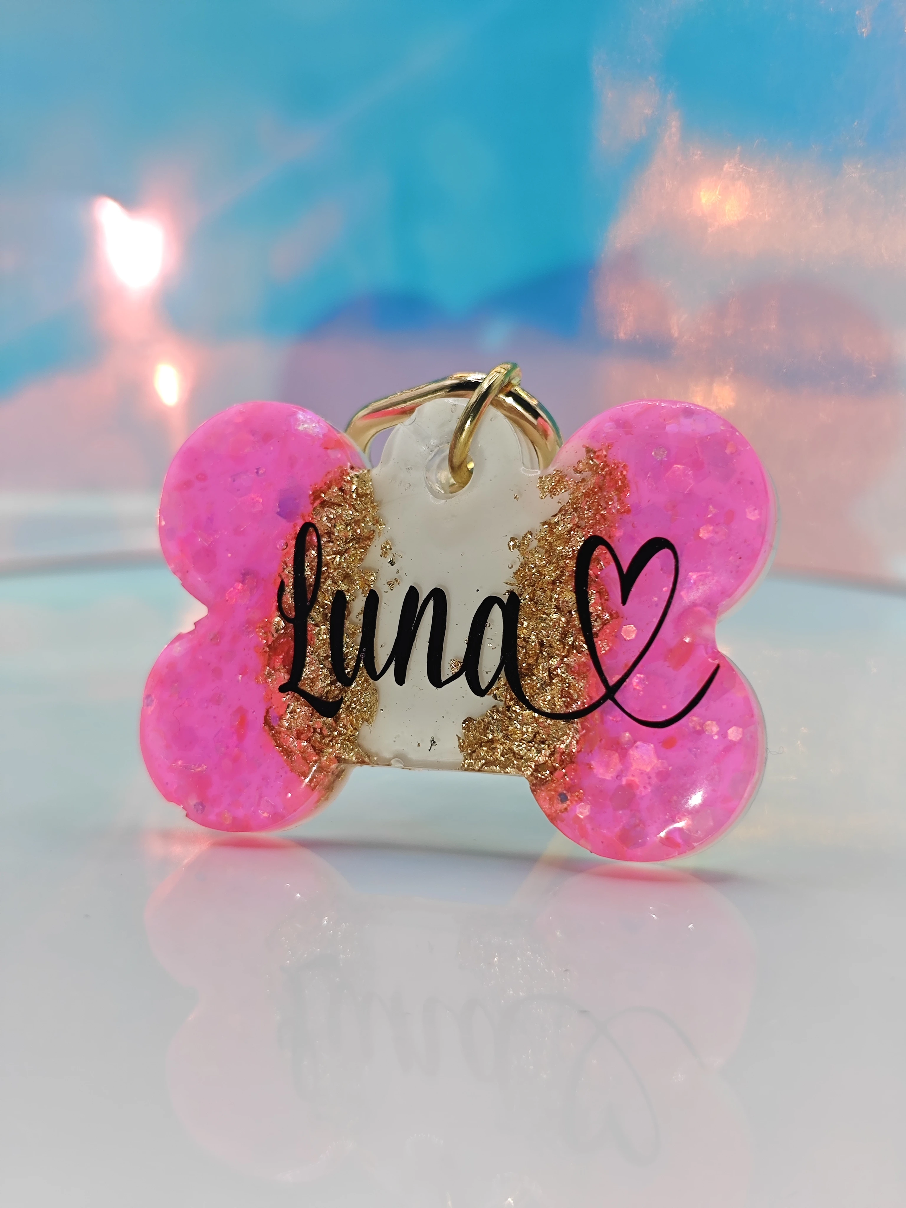 Placa para perro personalizada "Luna" con corazón, forma de hueso, color rosa brillante y detalles dorados.
