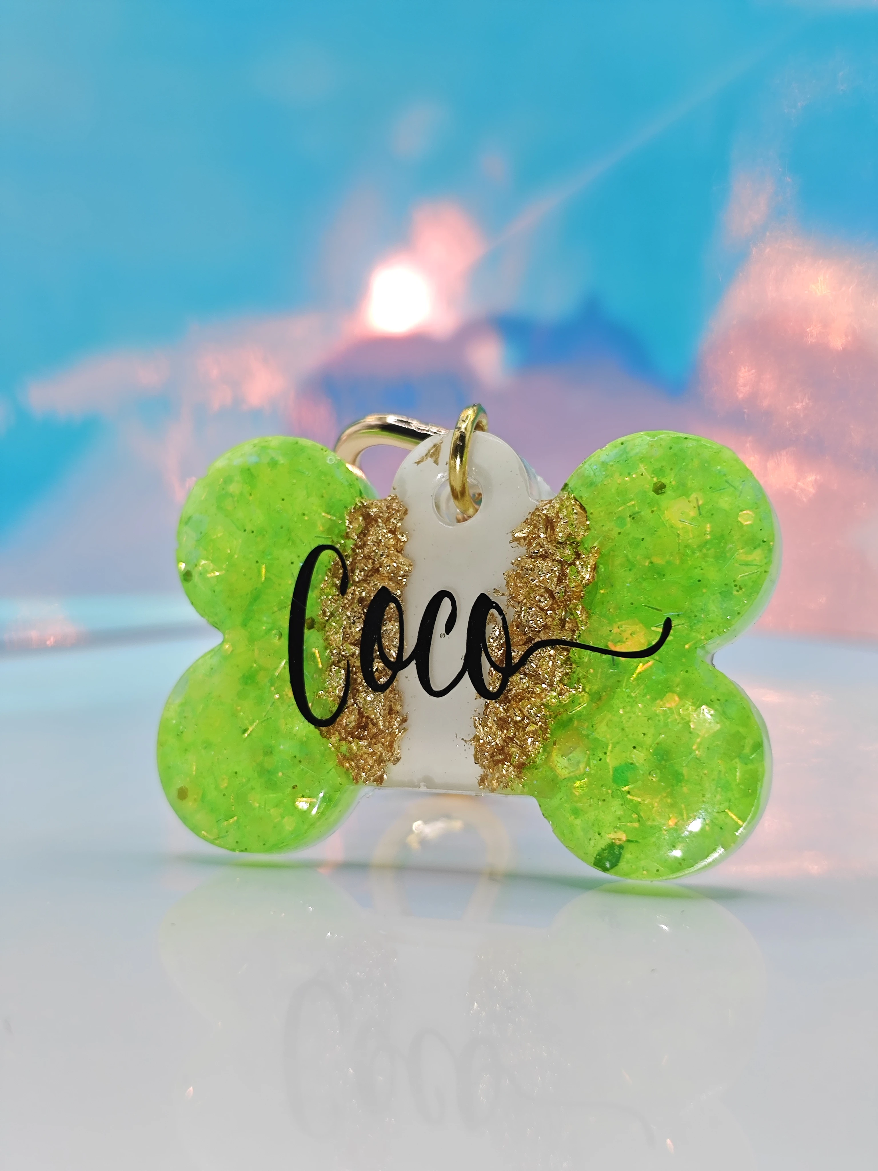 Placa hueso verde con nombre "Coco" en negro, detalles dorados, para collar de mascota.