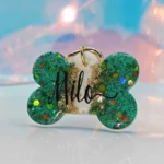 Placa de mascota de resina en forma de hueso, color verde con brillos y nombre "Milo" en negro.