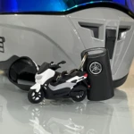 Llavero en 3D de moto Yamaha NMAX blanca y negra junto a su llave, sobre superficie reflectante.