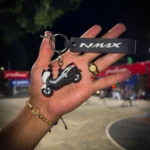 Llavero 3D moto NMAX gris con blanco y accesorio de corona dorada en mano.
