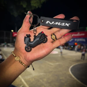 Llavero 3D negro de moto NMAX en mano con pulsera dorada.
