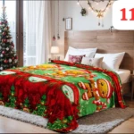 Cobija navideña decorativa con diseño de galletas de jengibre y árboles, en tonos verde y rojo, sobre una cama.