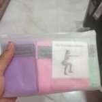 Bandas de resistencia para caderas en tela, talla L, morado y rosa, en empaque transparente.