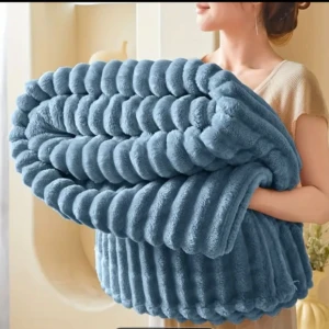 Manta polar felpa de conejo azul con textura acanalada, sostenida por una mujer.