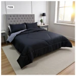 Edredón doble faz negro con rayas finas, dos almohadones a juego, sobre cama doble y alfombra crema.