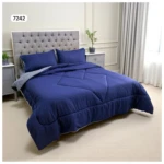 Edredón doble faz azul marino con rayas verticales y diseño acolchado, sobre cama doble con almohadas a juego.