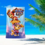 Toalla infantil Paw Patrol The Movie con Chase y Skye sobre fondo de playa y palmeras.