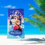 Toalla infantil de playa Frozen con Elsa, Anna y Olaf sobre fondo azul y palmeras.