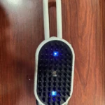 Cepillo Panda blanco para mascotas con vapor, dos luces LED azules, sobre superficie de madera.