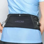 Riñonera deportiva negra para correr con logo KOM, ajuste en cintura, ideal para deportistas.