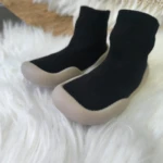 Zapatos respetuosos negros para bebé con suela beige, estilo botín, ideales para primeros pasos.