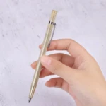 Bolígrafo dorado con textura diamantada y clip plateado, sostenido en mano, listo para corte de vidrio.