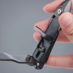Corta uñas metálico negro con depósito para residuos, abierto y en uso.