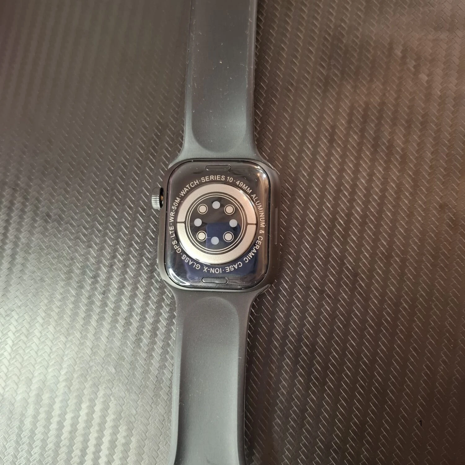Reverso de reloj inteligente gris Apple Watch Series 9 49mm aluminio con banda deportiva.