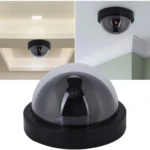 Cámara domo falsa negra con LED rojo intermitente en techo, disuade intrusos.