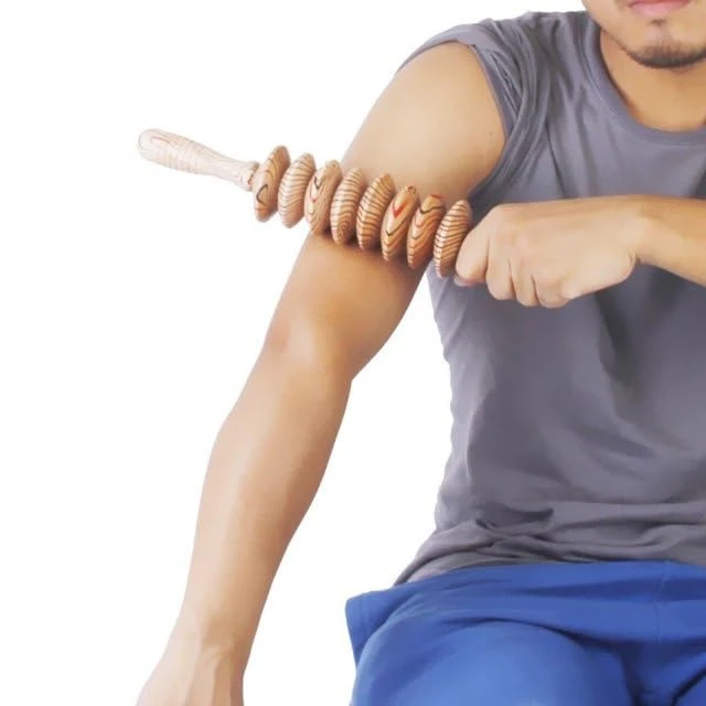 Hombre con masajeador de madera en forma de rodillo con discos acanalados aplicándolo en el brazo.
