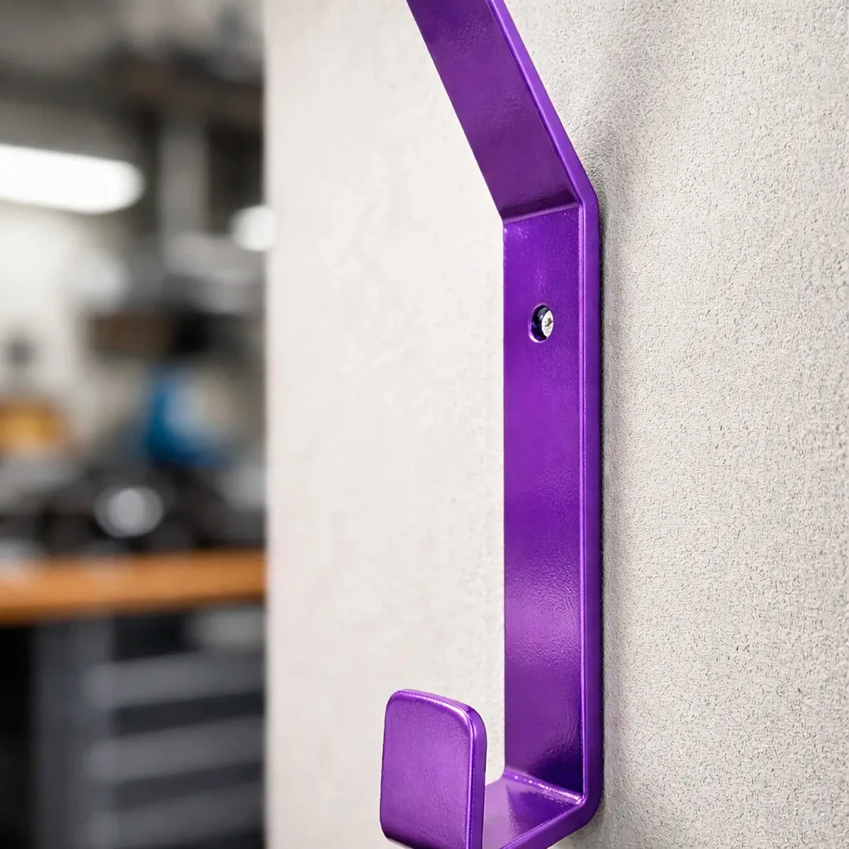 Gancho morado metálico para colgar casco de moto en pared.