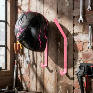 Set x2 soportes para casco de moto color rosa neón, colgados en pared de madera con herramientas.