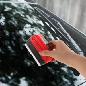 Limpia vidrios de auto magnético rojo y negro en acción.