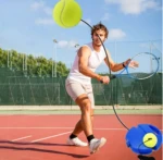 Hombre entrenando tenis con pelota atada a base azul en cancha roja.