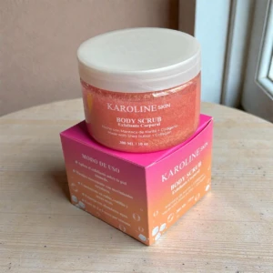 Exfoliante corporal Karoline Skin rosado con brillo, en envase y caja, ideal para uso en ducha.