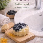 Jabón artesanal de carbón activado y cúrcuma en forma de flor sobre tabla de madera con cepillo y cúrcuma en polvo.
