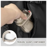 Jabonera portátil de viaje transparente con tapa y jabón dentro de un bolsillo de mochila.